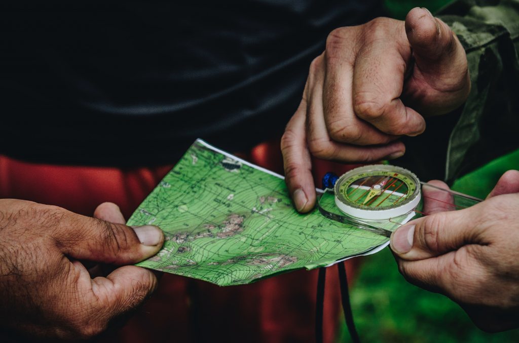 Two persons holding a map and compass.