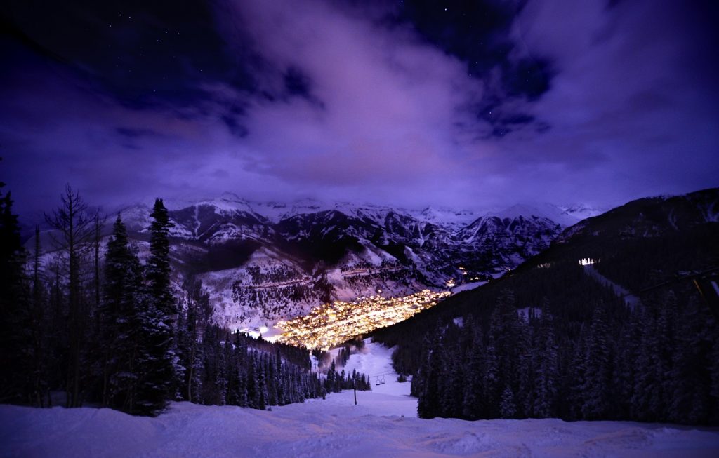 snowy grounds and purple sky with distant lights during nighttime