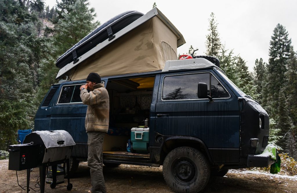 a man in K&Uuml;HL pants standing in fron of blue camper van