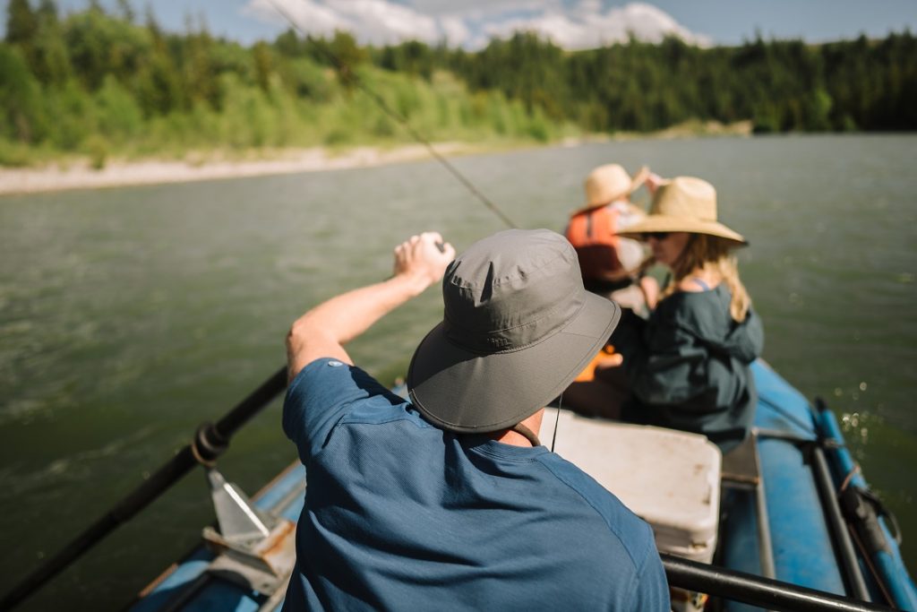 man wearing K&Uuml;HL sun hat holding paddle on raft