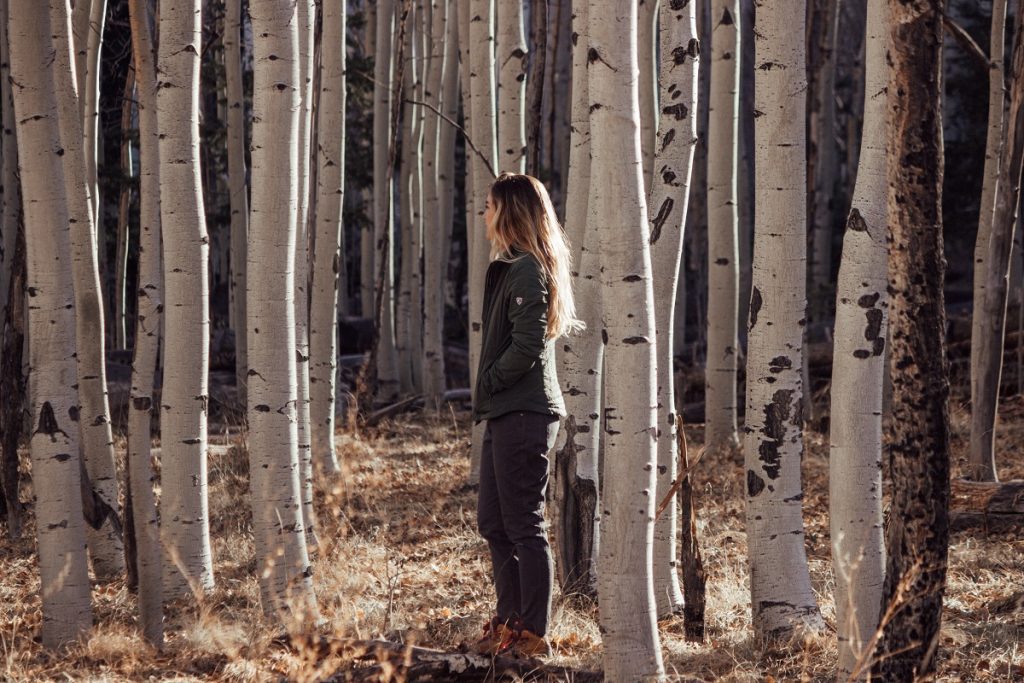 woman in K&Uuml;HL jacket standing between white trees