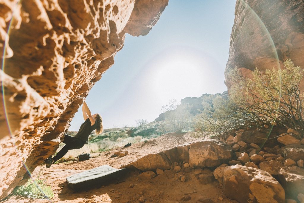 woman in K&Uuml;HL leggings climbing on red rock