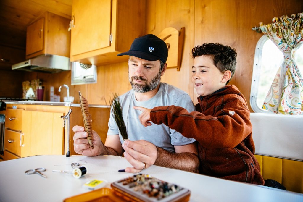 man in K&Uuml;HL shirt showing feathers to his son in camper