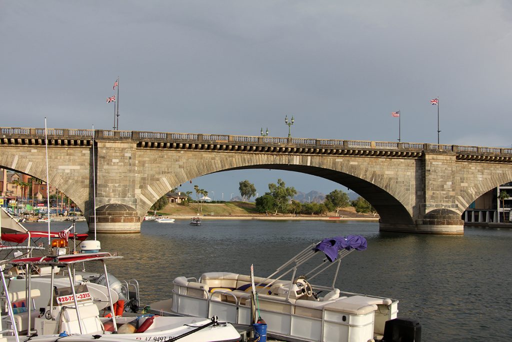 white pontoon boat on lake with bridge in the background